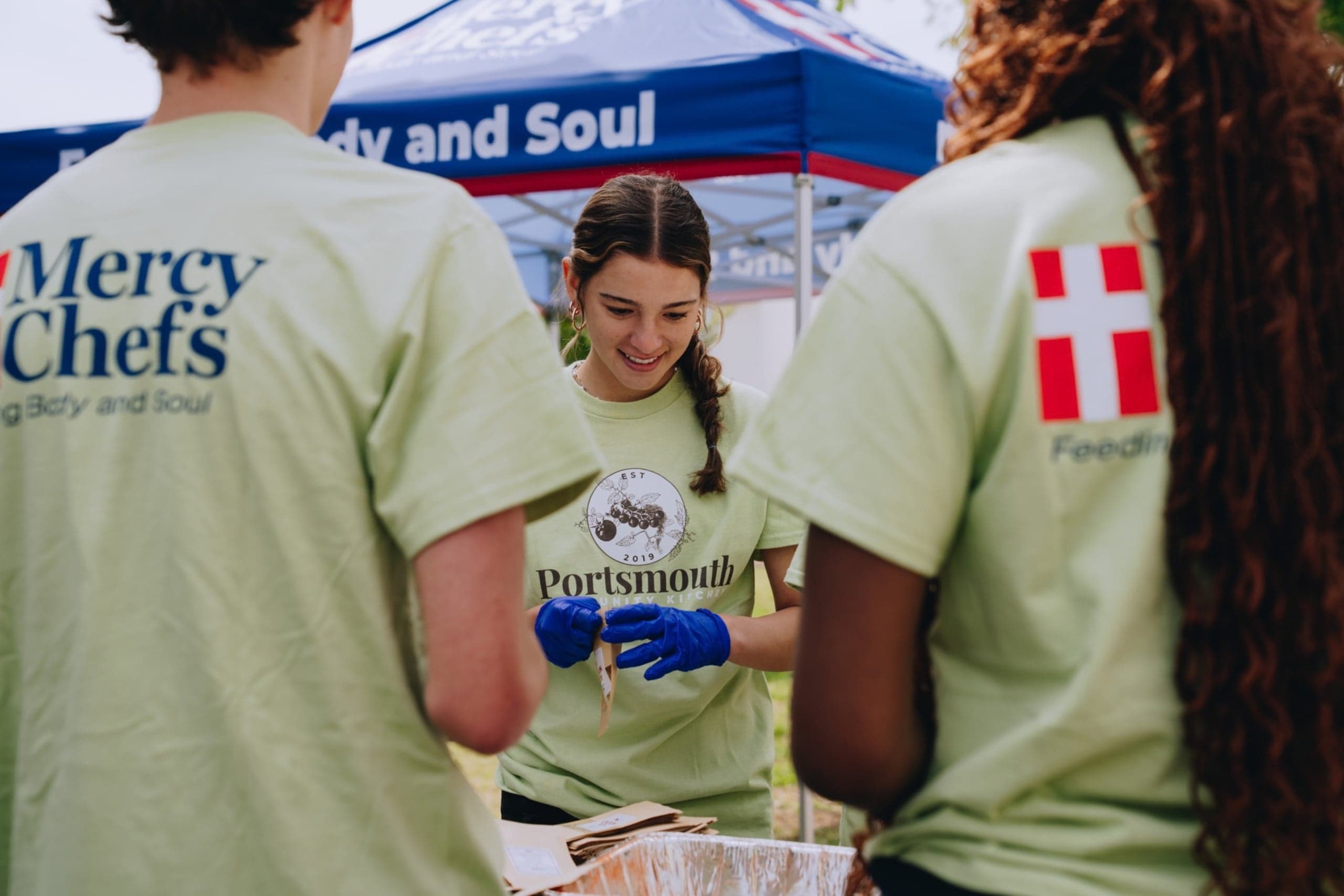 Portsmouth Community Kitchen volunteer smiles while holding a spice bag
