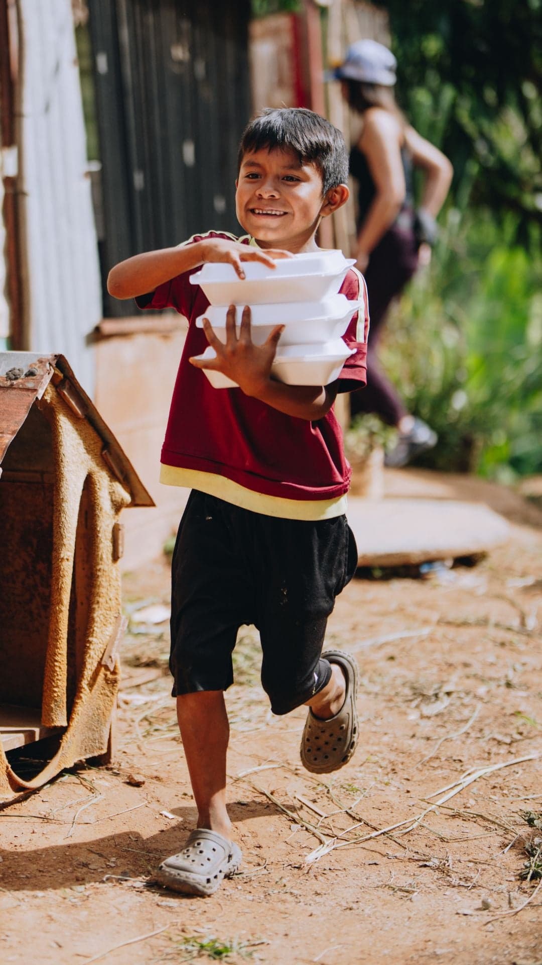 A child in Venezuela smiles as he carries hot meals.