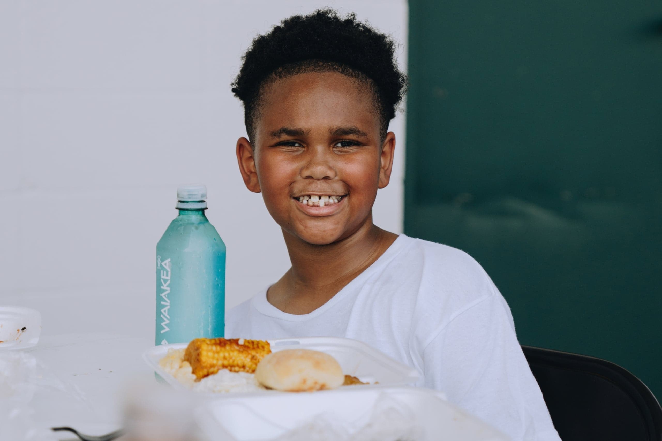 A boy smiles as he enjoys a hot meal at summer camp