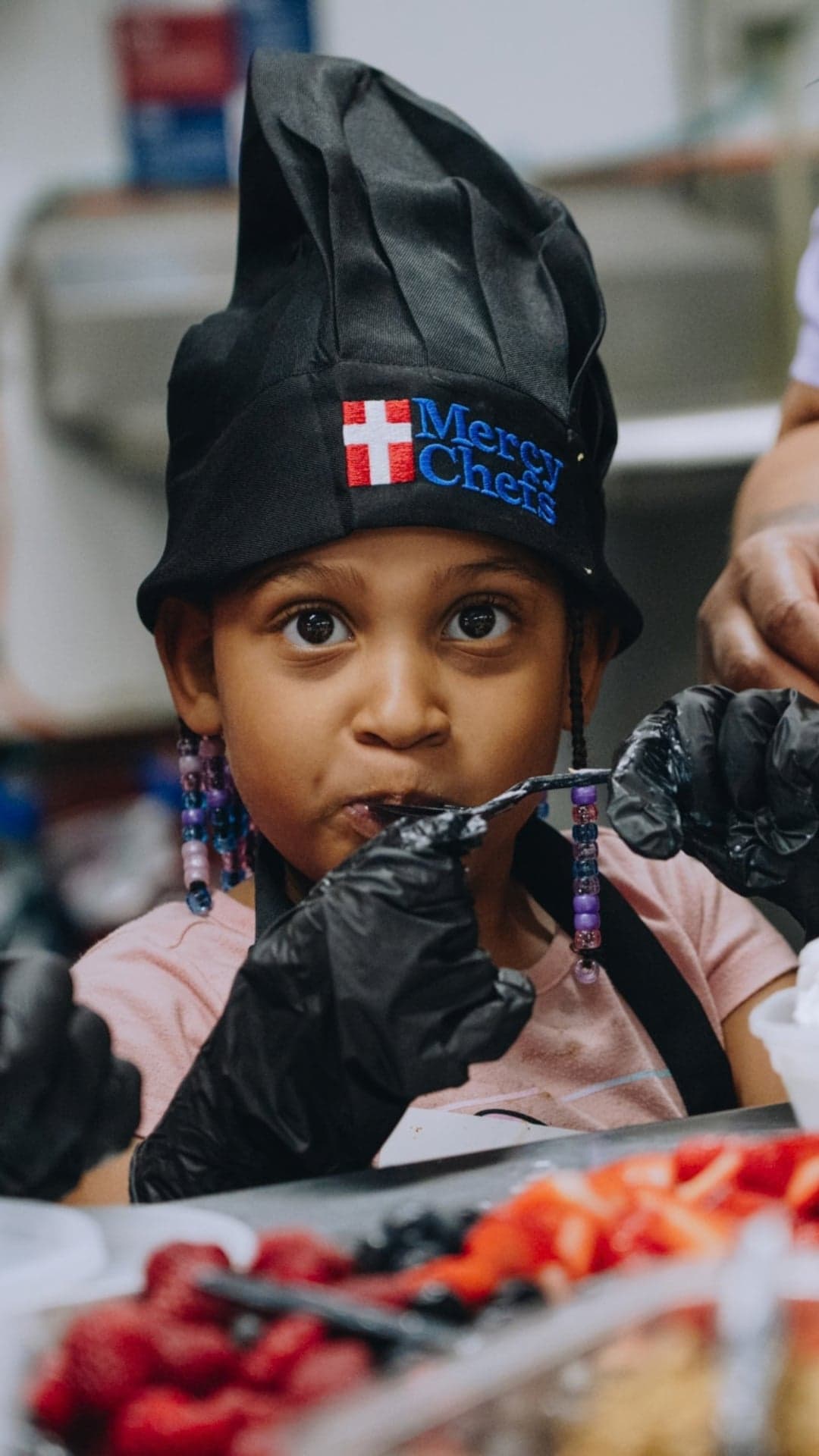 Young girl tries a strawberry during a cooking class