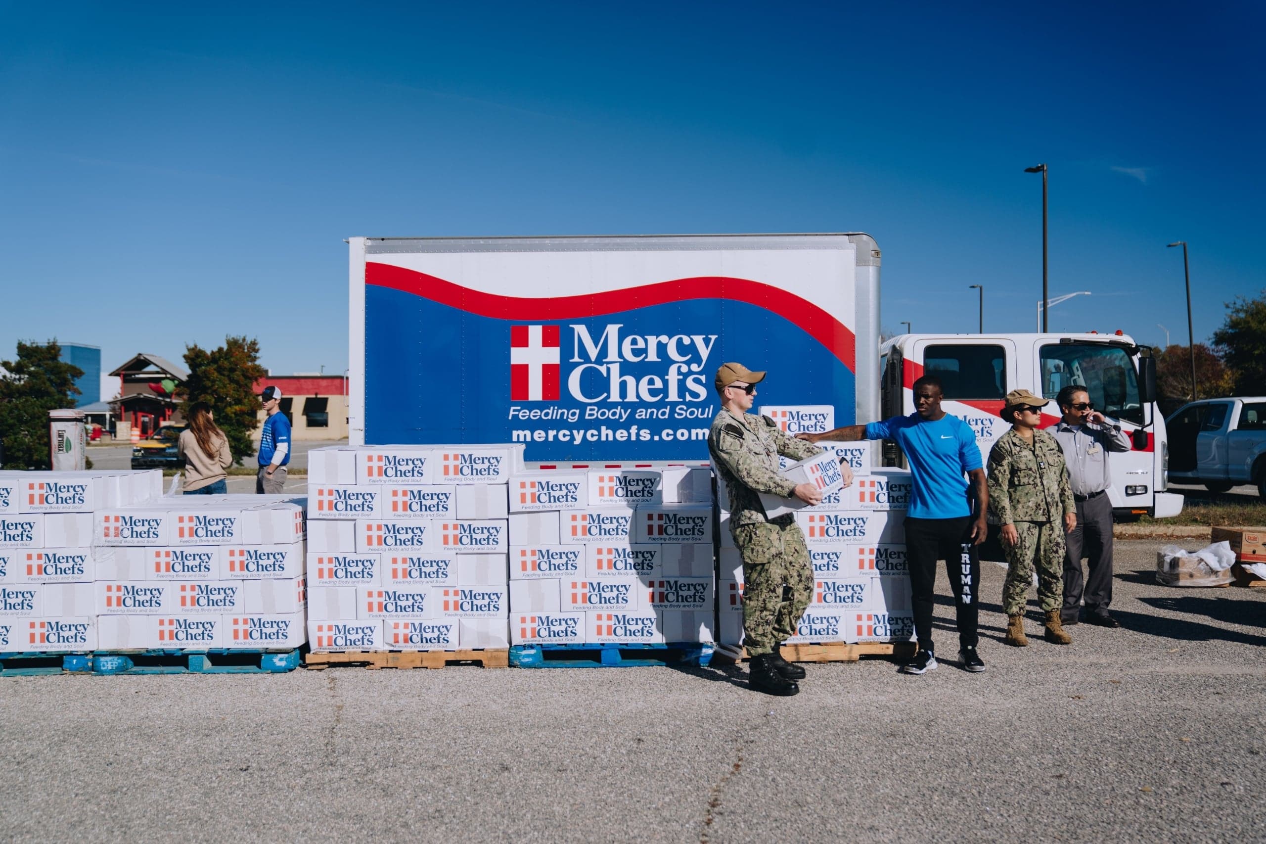 A military service member carries a Mercy Chefs' Family Grocery Box.